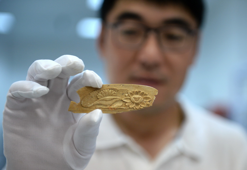 5月15日，考古工作者展示西安隋唐長安城東市遺址出土的蓮花紋骨梳柄。新華社記者 李一博 攝