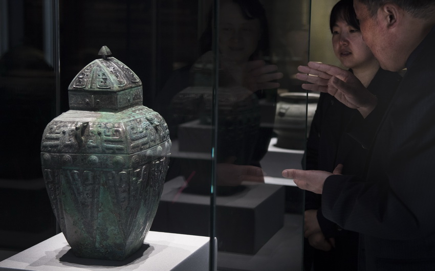 4月16日，城固縣博物館館長茍保平（右）在向游人介紹商獸面紋方罍。 新華社記者 陶明 攝
