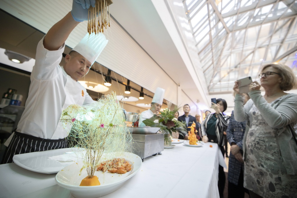 10月14日，在芬蘭赫爾辛基的郵政大樓餐廳內，中國烹飪協會廚師向來賓展示拔絲紅薯。