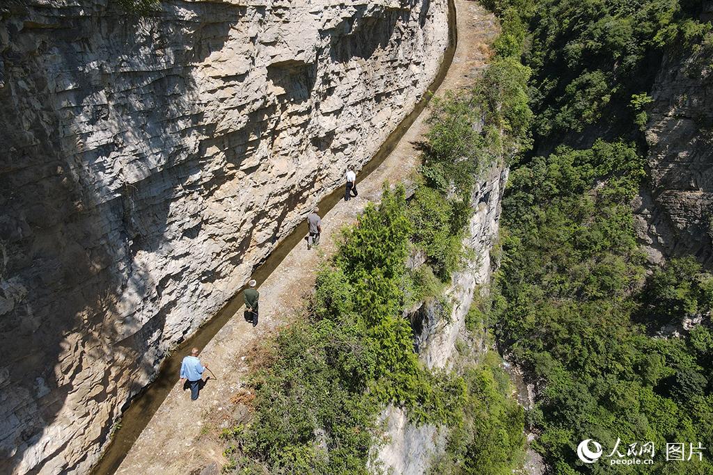 8月25日，當年參與修渠的老人們在貴州省畢節市七星關區生機鎮鎮江社區的鎮江大溝上進行巡渠。（無人機照片）