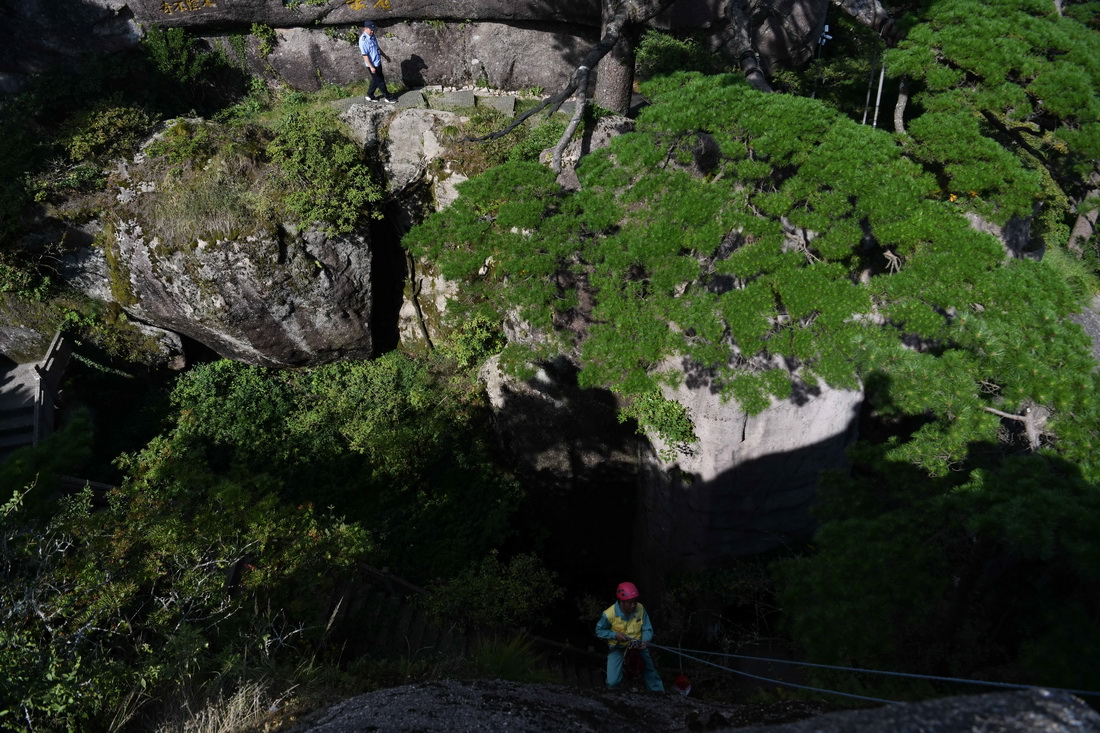 8月15日，李培生（下）在黃山風景區的懸崖峭壁間清撿垃圾，胡曉春（上）在迎客松附近巡查。新華社記者 張端 攝