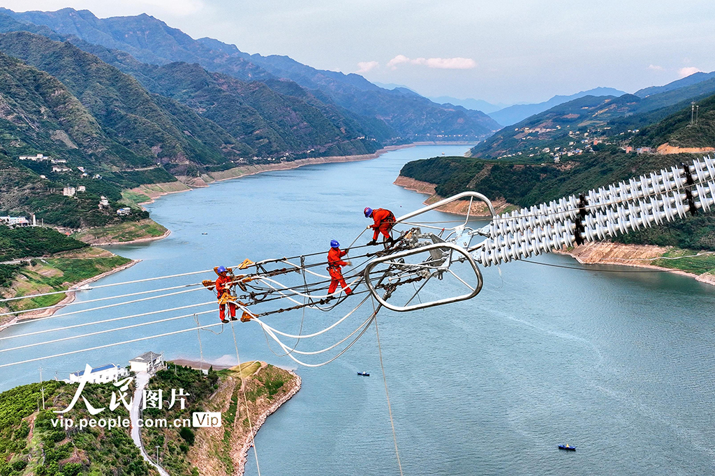2022年8月20日，湖北省恩施土家族苗族自治州巴東縣東瀼口鎮綠竹筏村，電力工人冒著40℃以上的高溫跨越長江施工作業。