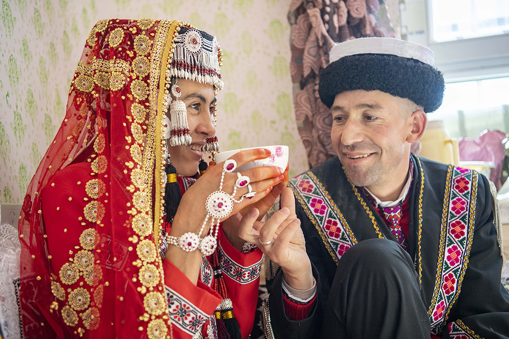 在位于縣城的新家中，新郎買熱買提汗·青鐵木爾為新娘古麗汗·贊加比力送上一碗奶茶（3月20日攝）。新華社記者 胡虎虎 攝