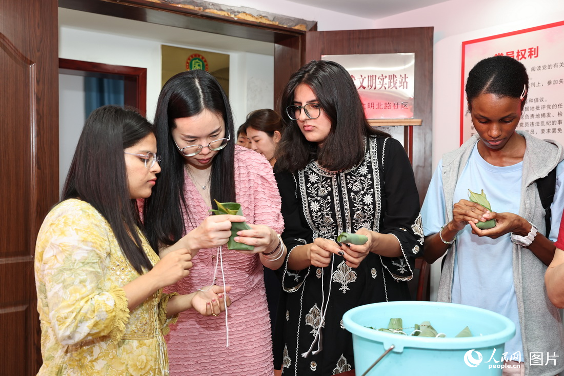 6月20日，江西省中醫藥大學開展豐富多彩的“我們的節日·端午”主題活動，該校的留學生們走進社區，在工作人員的指導下學習包粽子，迎接傳統節日的到來。 人民網記者 時雨攝