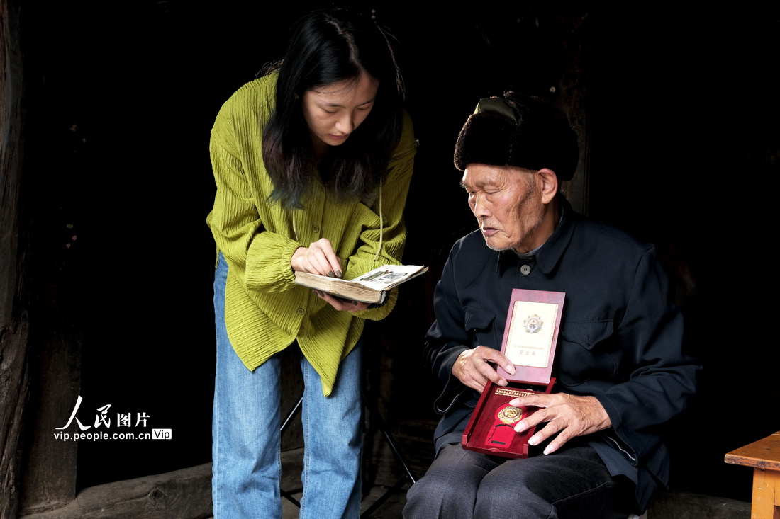 2023年7月8日，采訪者向老兵甘為美詢問老照片中的故事。杜江攝（人民圖片網）