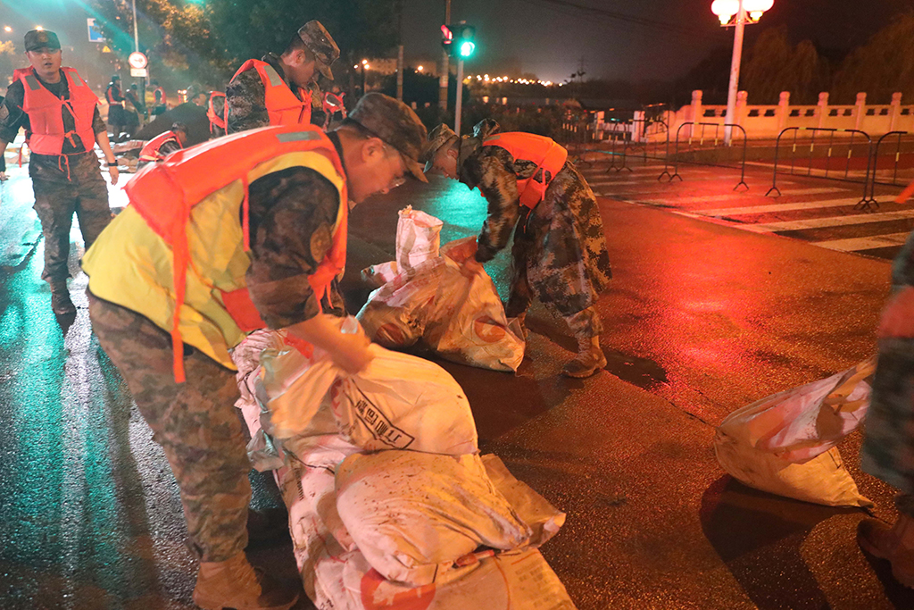 中部戰區空軍某部官兵在北京市懷柔區廟城鎮懷河岸邊裝填沙袋（8月1日攝）。新華社發（白玉辰 攝）