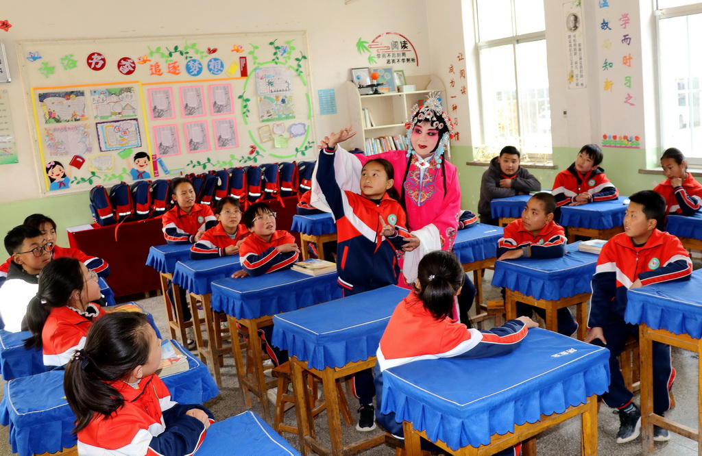 3月27日，在甘肅省平涼市靜寧縣威戎鎮中心小學，秦腔演員在指導學生做秦腔動作。新華社發（王毅攝）