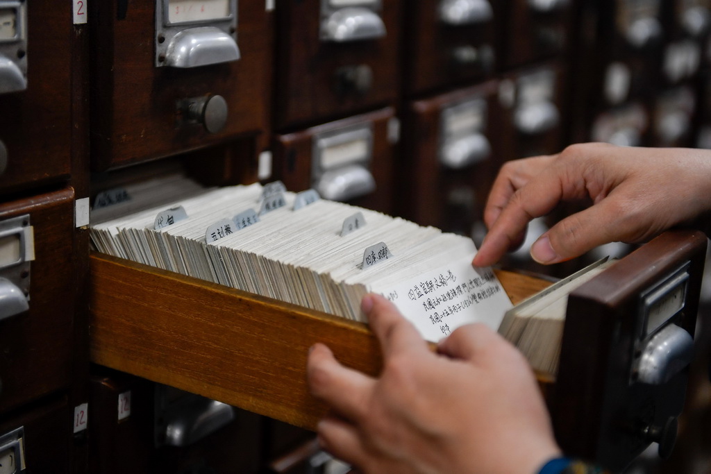 吉林大學圖書館古籍部主任王麗華在線裝書庫內翻看分類目錄尋找古籍（4月19日攝）。