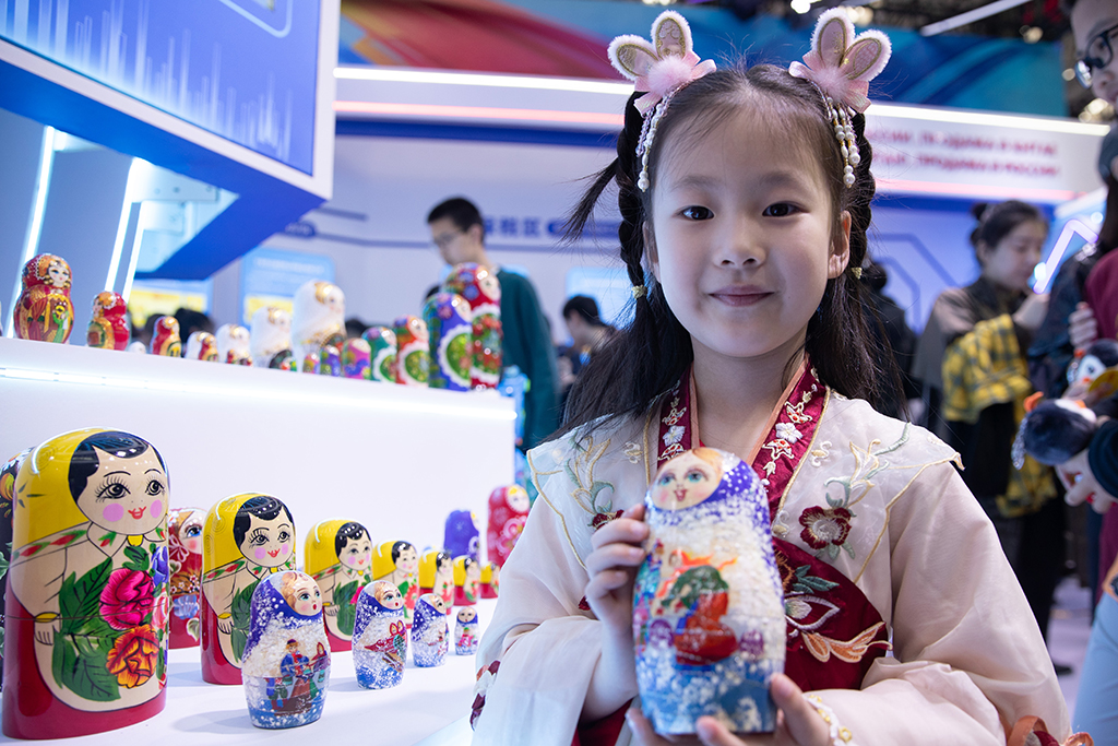5月19日，在第八屆中俄博覽會現場，一名小朋友拿著俄羅斯套娃拍照。
