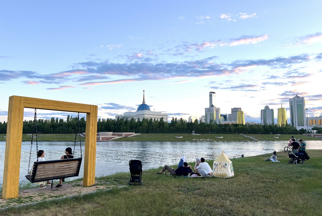 6月29日，人們在哈薩克斯坦首都阿斯塔納伊希姆河畔休息。新華社記者 龐興雷 攝