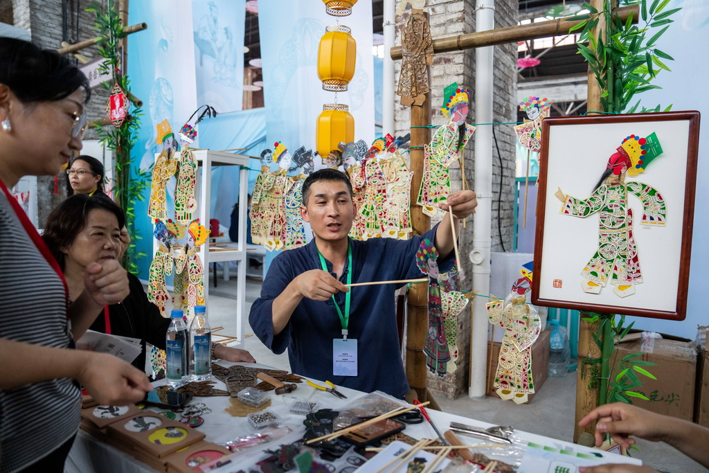 9月21日，在第三屆湖南非遺博覽會上，參展商（右）向觀眾介紹紙影制作技藝。