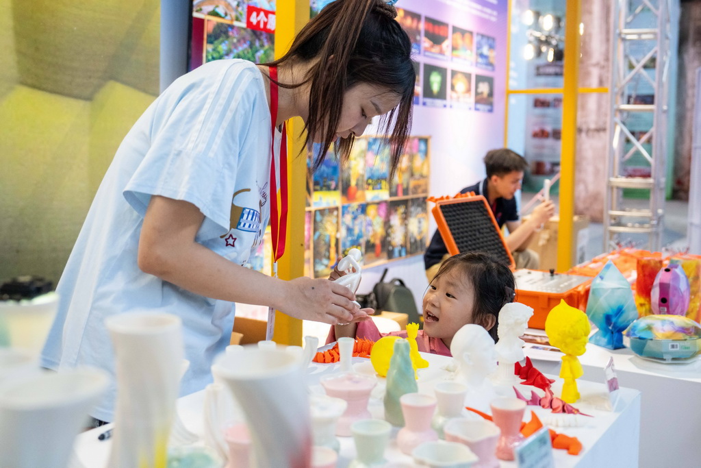 9月21日，在第三屆湖南非遺博覽會上，參展商（左）向觀眾介紹3D打印非遺文創產品。