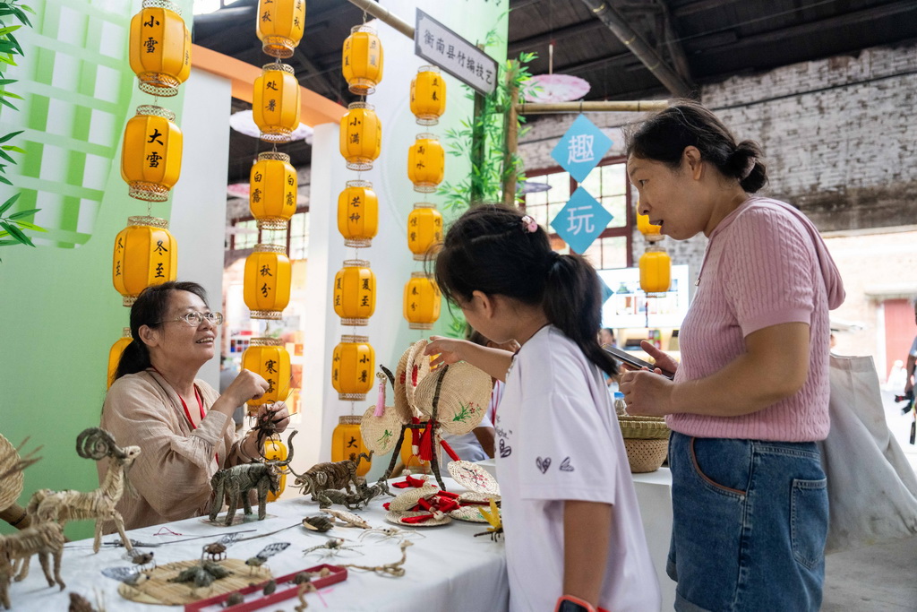 9月21日，在第三屆湖南非遺博覽會上，參展商（左）向觀眾介紹衡山棕編。