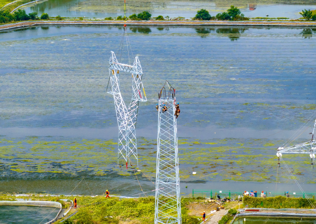 9月24日，直升機在江蘇省興化市昌榮鎮上空協助鐵塔架設作業（無人機照片）。新華社發（周社根攝）
