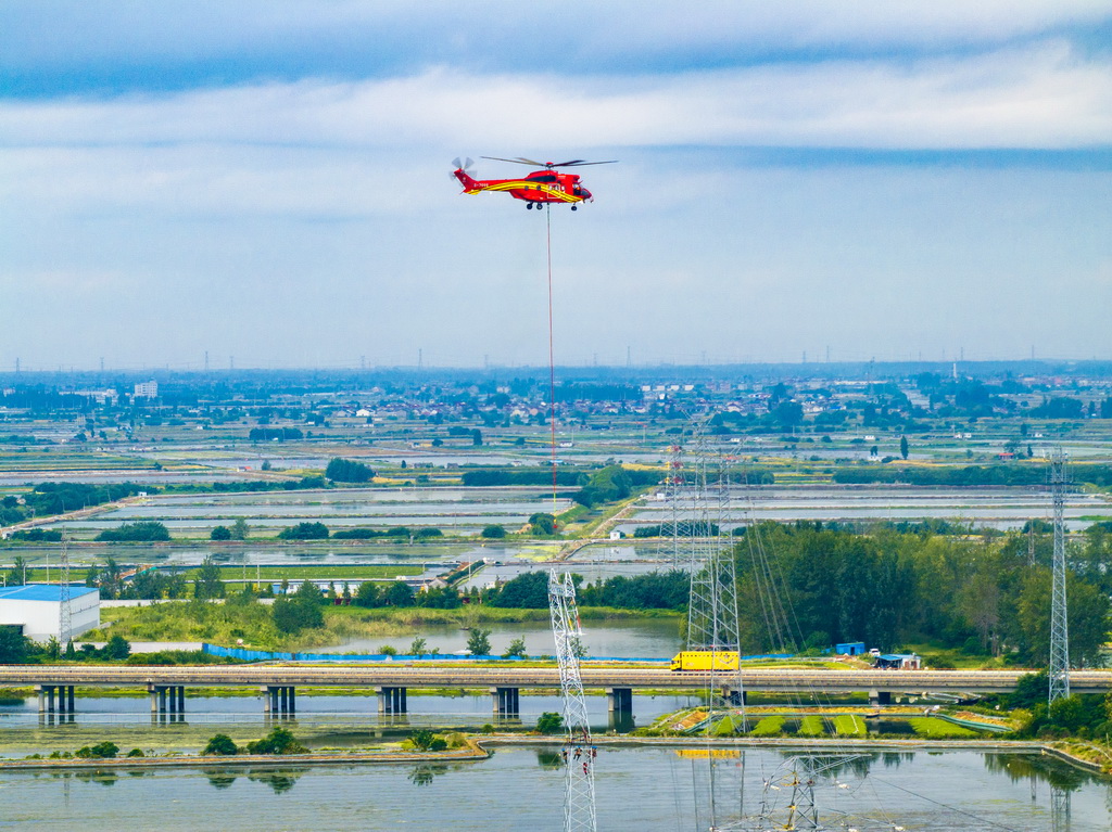 9月24日，直升機在江蘇省興化市昌榮鎮上空協助鐵塔架設作業（無人機照片）。新華社發（周社根攝）
