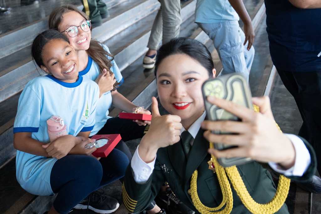 9月23日，在巴西首都巴西利亞高等防務學院舉行的“中國日”活動上，中國人民解放軍國際傳播代表團的軍樂分隊隊員與巴西觀眾合影。新華社記者 王天聰 攝