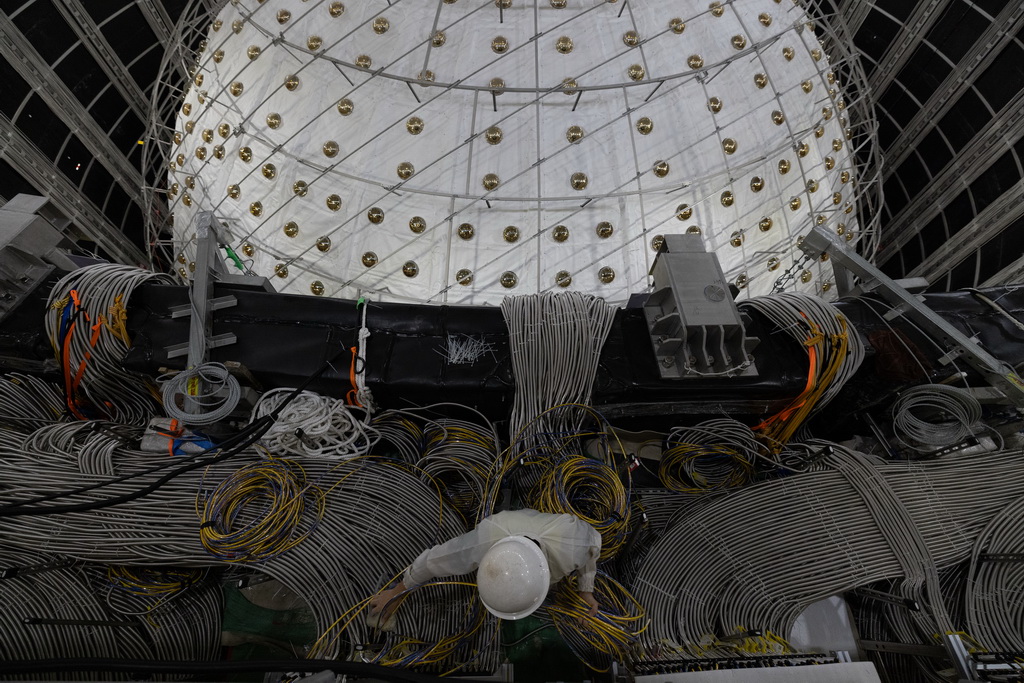 10月9日，工作人員在中心探測器水池邊整理電子學線纜。