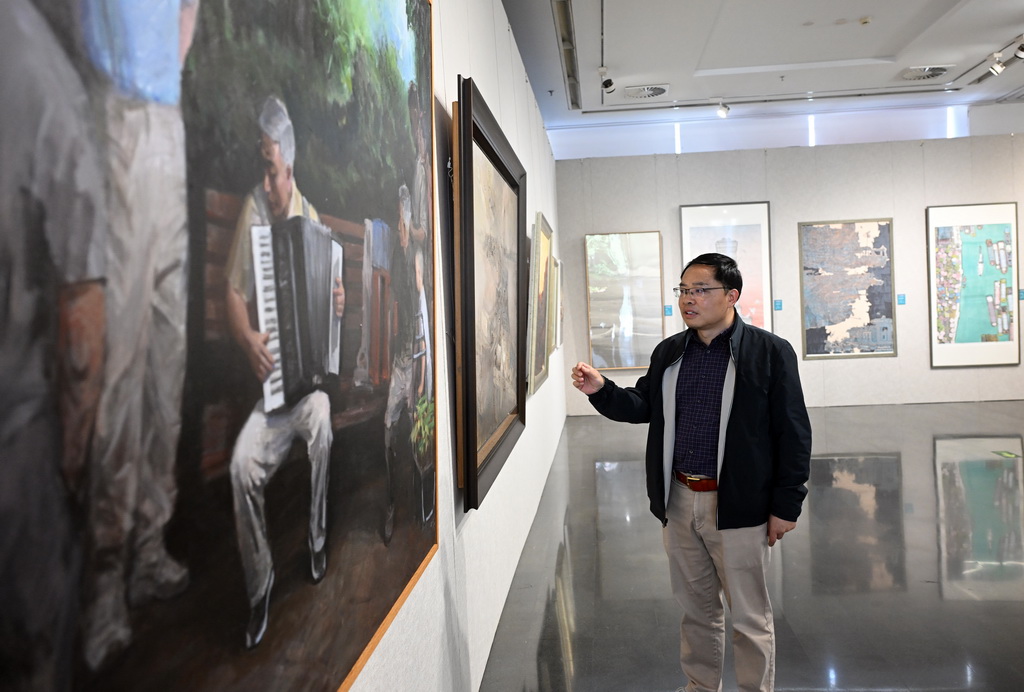 10月15日，策展人譚國亮介紹展出的畫作。