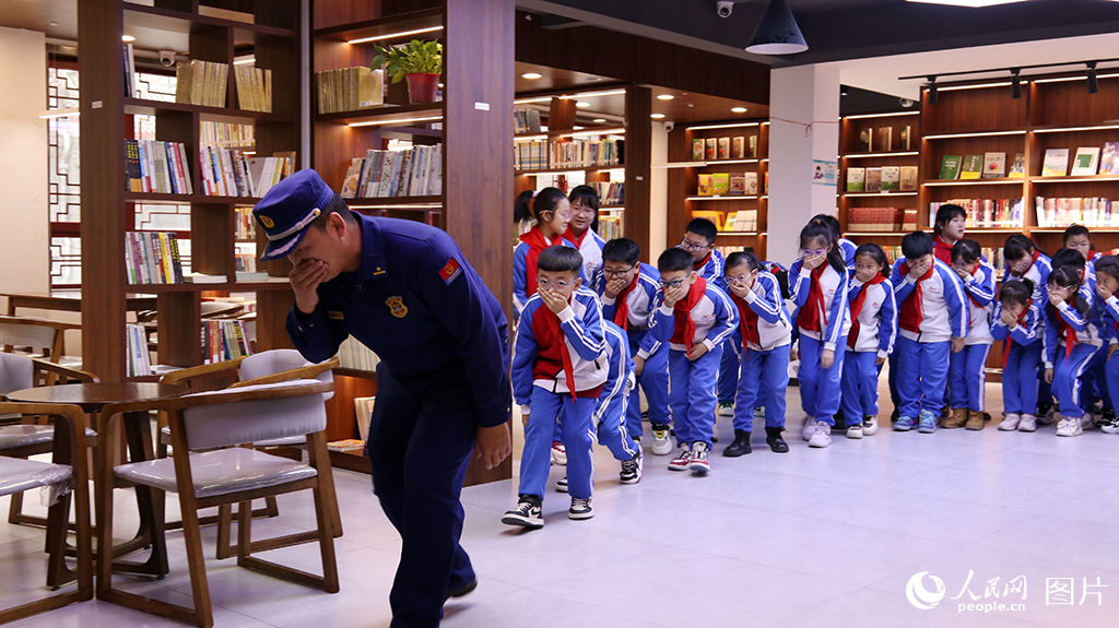 11月8日，吉林省洮南市文化廣播電視和旅游局聯合洮南市消防救援局、洮南市實驗小學深入博物館、洮南書局開展“全民消防 生命至上”主題消防安全教育活動?；顒蝇F場，消防指戰員指導小學生如何在公共場館正確疏散。人民網 李成偉攝
