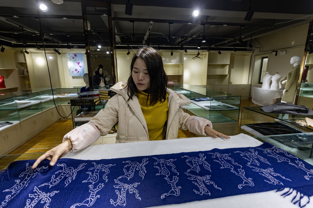 日土縣白山羊絨產業展示中心的工作人員在展示印有日土巖畫圖案的“指環披肩”（11月16日攝）。新華社記者 姜帆 攝