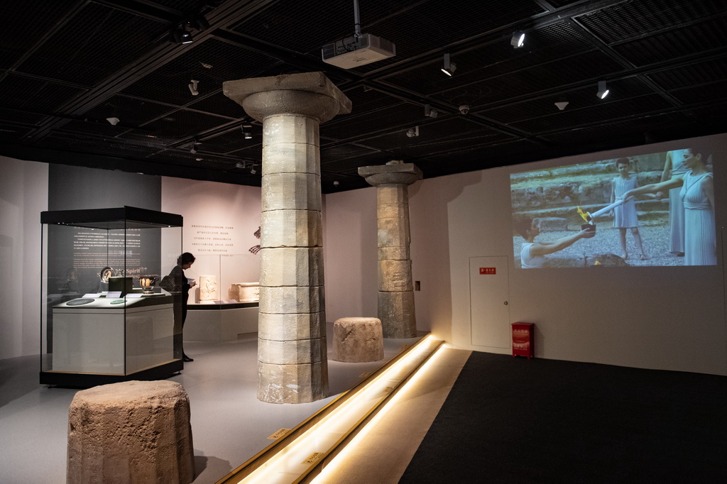 這是11月20日拍攝的“希臘人——從阿伽門農到亞歷山大”展廳一角，這里在播放2008年在希臘奧林匹亞舉辦的北京奧運圣火取火儀式視頻。