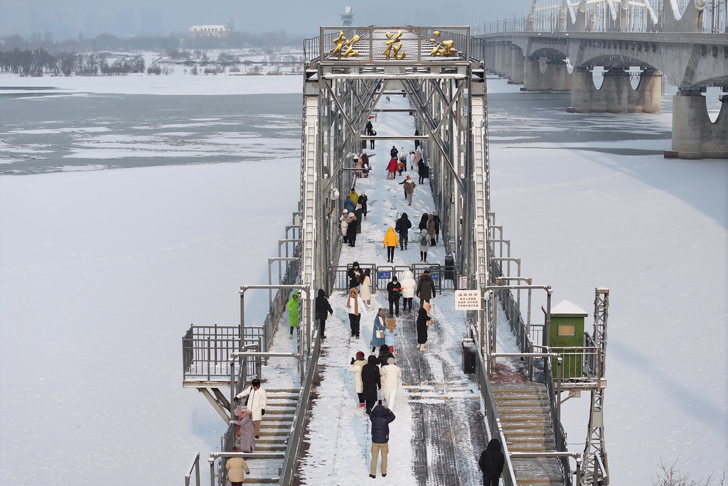 11月28日，松花江干流哈爾濱段封江，游人在濱洲鐵路橋上打卡拍照（無人機照片）。