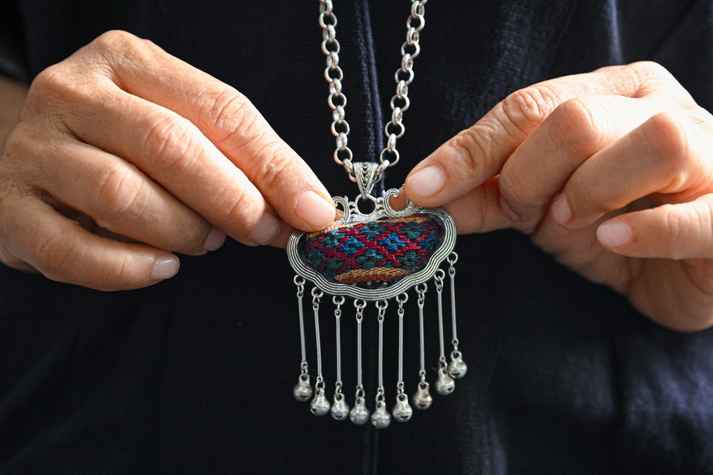 黎族織娘在位于海南省東方市東河鎮的家中展示含有黎錦元素的吊墜（2023年6月7日攝）。新華社記者 蒲曉旭 攝