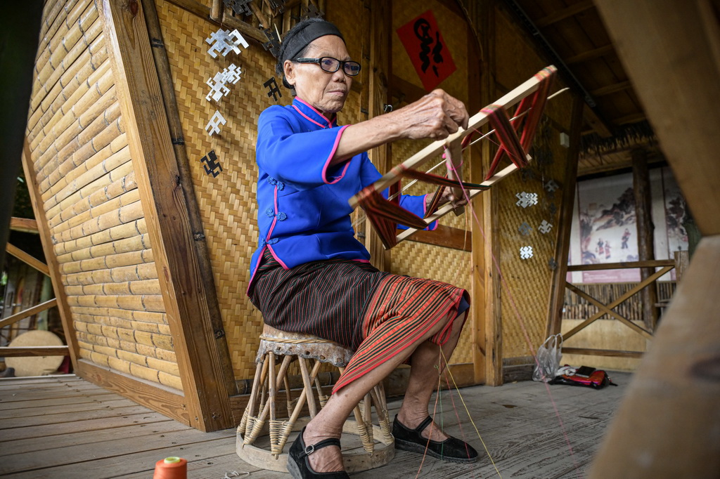 黎族老人在位于海南保亭的檳榔谷文化旅游區展示黎族織錦過程中的繞線工藝（2024年11月4日攝）。新華社記者 蒲曉旭 攝