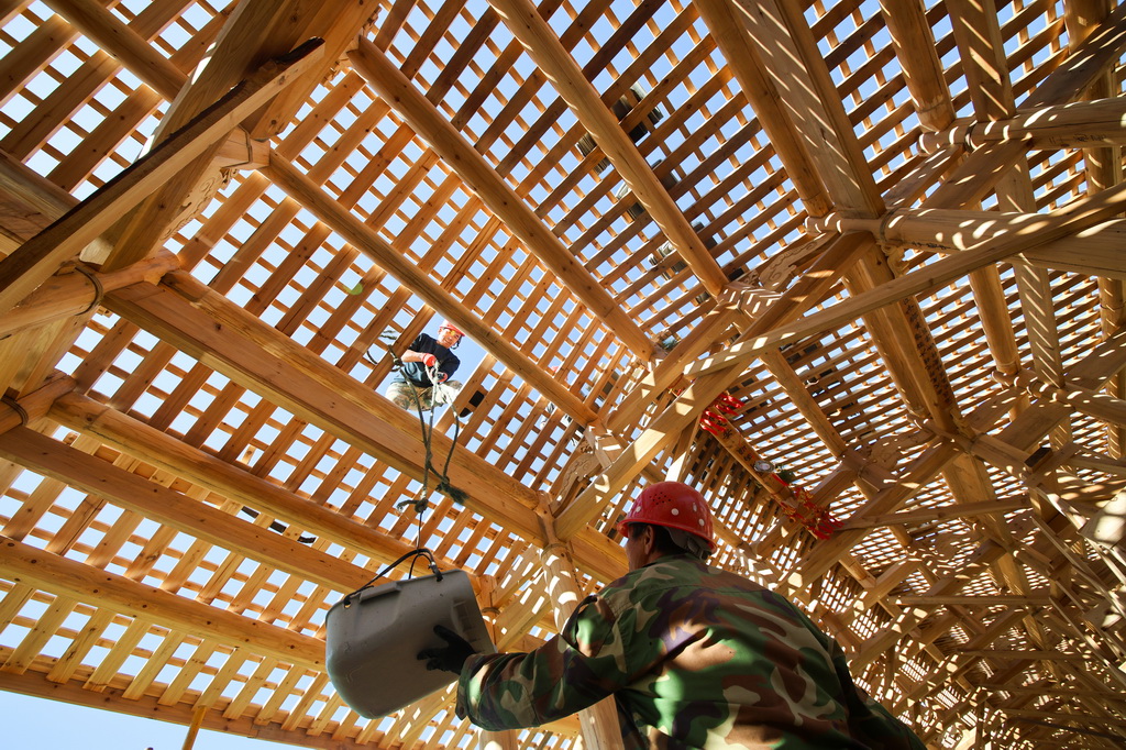 在福建省屏南縣長橋鎮，工匠們在修復萬安橋時吊裝瓦片，鋪設廊屋屋頂（2023年11月29日攝）。新華社發（王志凌攝）