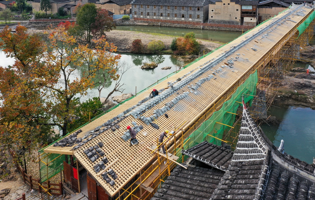 在福建省屏南縣長橋鎮，工匠在修復萬安橋時鋪設廊屋屋頂瓦片（2023年12月2日攝，無人機照片）。新華社發（王志凌攝）