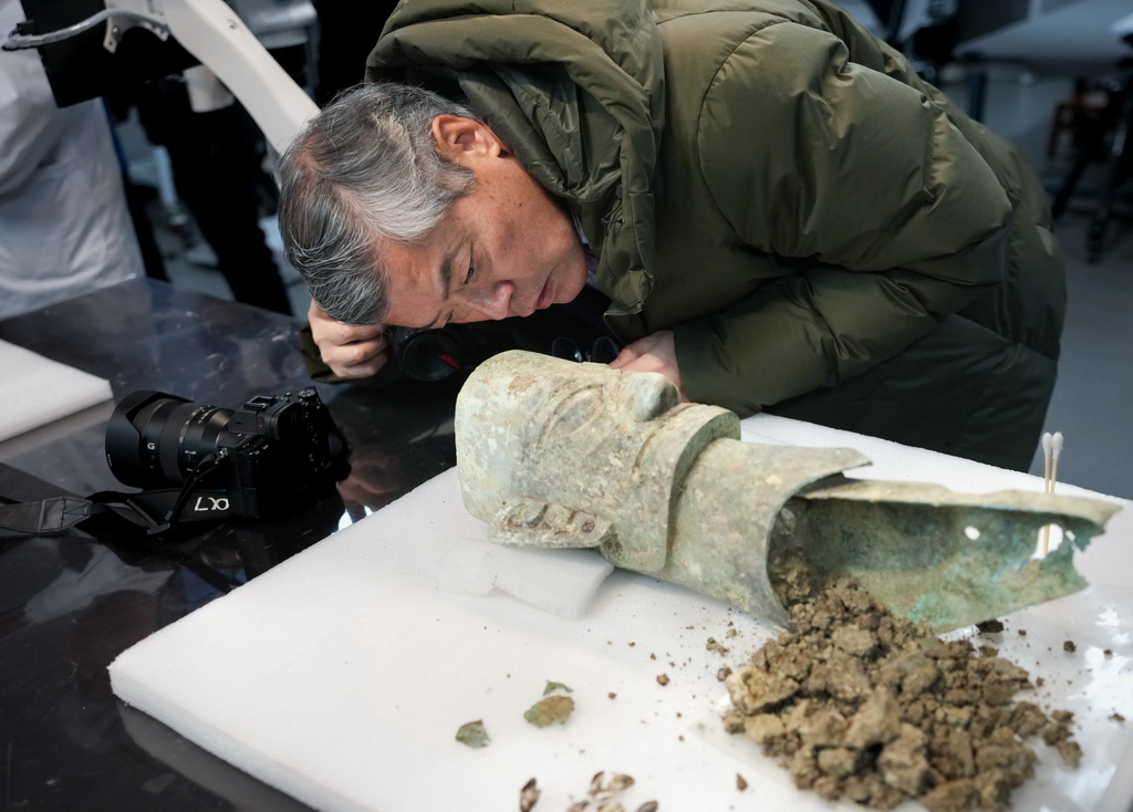 12月16日，在三星堆研究院，考古專家在仔細查看一件青銅面具。