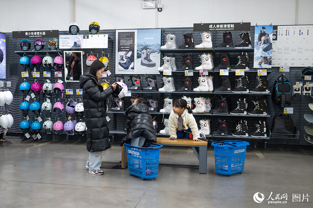 12月14日，在河北省三河市一商場，家長正在為孩子挑選滑雪頭盔。隨著冰雪運動不斷升溫，冰雪裝備產業也迎來發展黃金期。人民網記者 翁奇羽攝