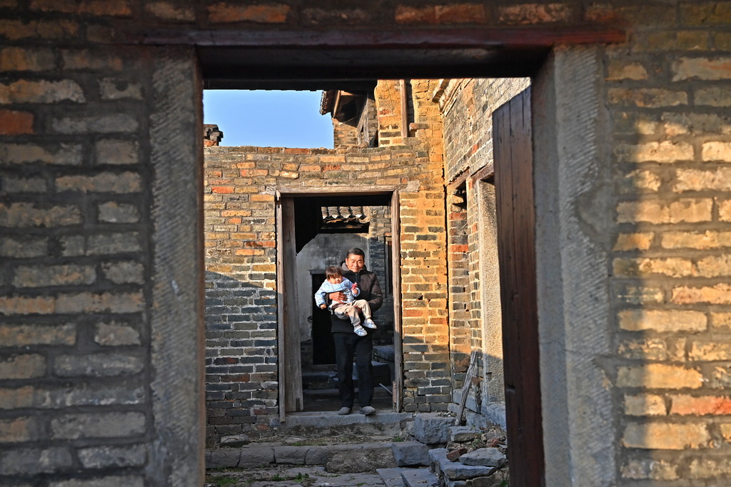 村民從金秀縣桐木鎮那安村龍騰屯一座古宅里走出（12月19日攝）。