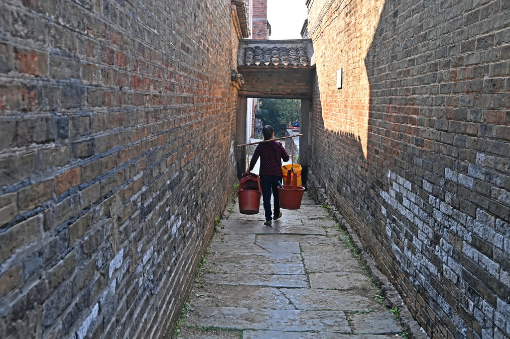 村民走在金秀縣桐木鎮那安村龍騰屯的古巷中（12月19日攝）。