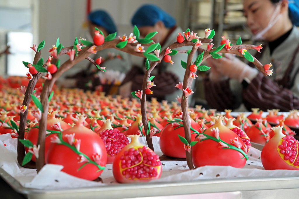 12月29日，民間藝人在山東省棗莊市“紅石榴”喜饃制作工坊捏制“紅石榴”喜饃上的裝飾物。新華社發（王海楠攝）