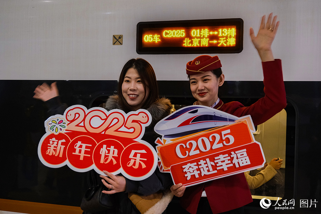 12月30日，乘務人員與旅客在北京南開往天津的C2025次列車前合影留念。