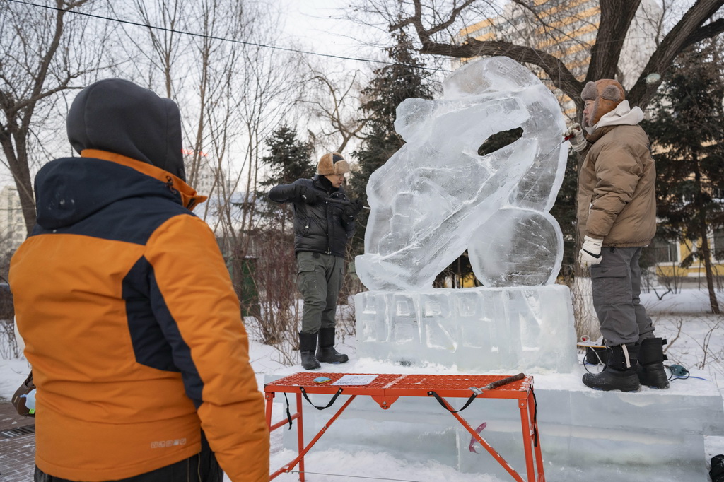 1月2日，在哈爾濱市道里區，冰雕師在兆麟公園內雕琢2025年哈爾濱亞冬會主題冰雕作品。