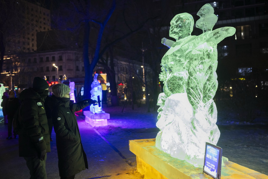 1月2日，在哈爾濱市兆麟公園，游客在冰燈藝術游園會園區內的冰燈前拍照。