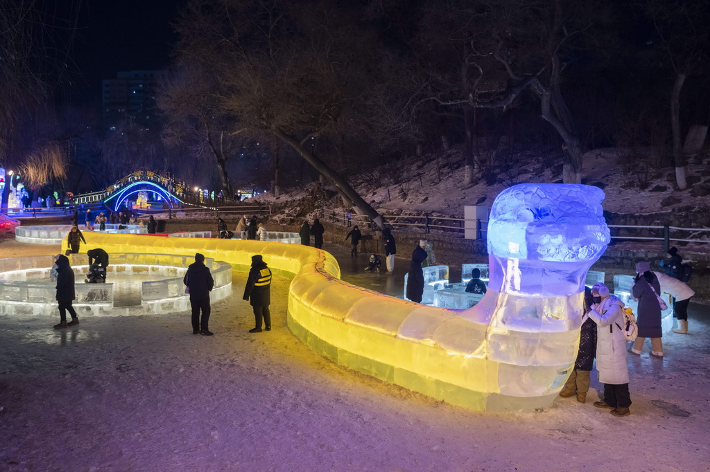 1月2日，在哈爾濱市兆麟公園，游客在冰燈藝術游園會園區內一處蛇形冰燈附近游玩。