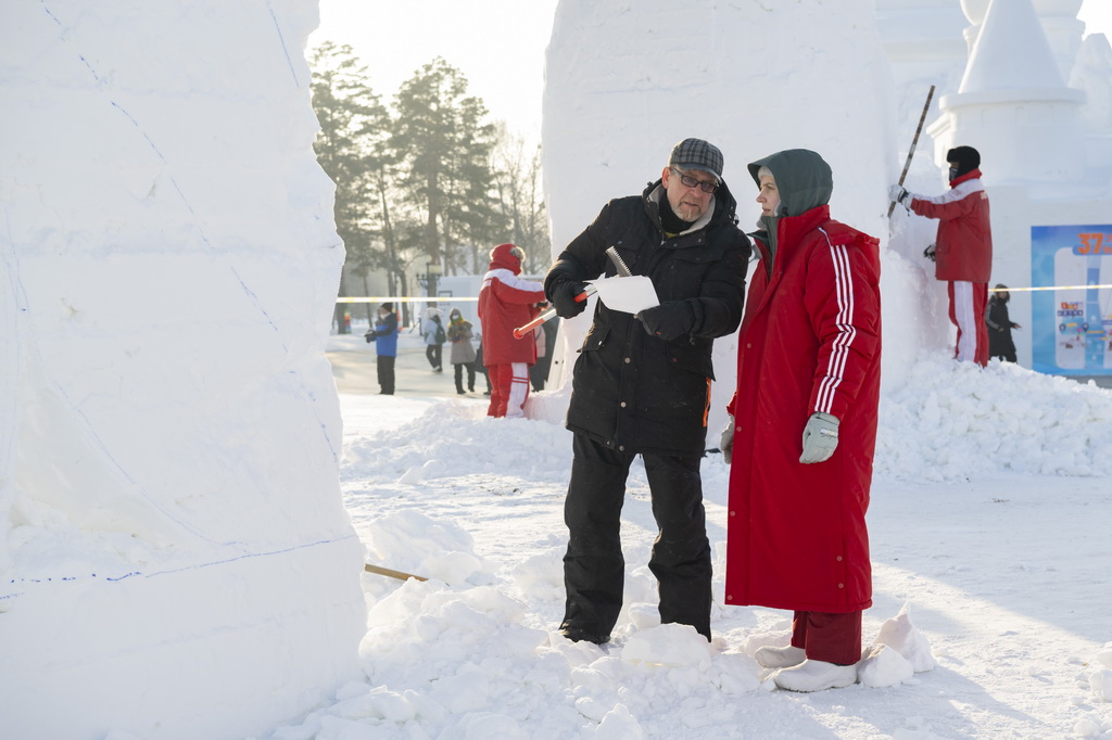 1月6日，在哈爾濱太陽島雪博會園區，參賽選手在雕刻雪雕作品的間隙交流。新華社記者 謝劍飛 攝