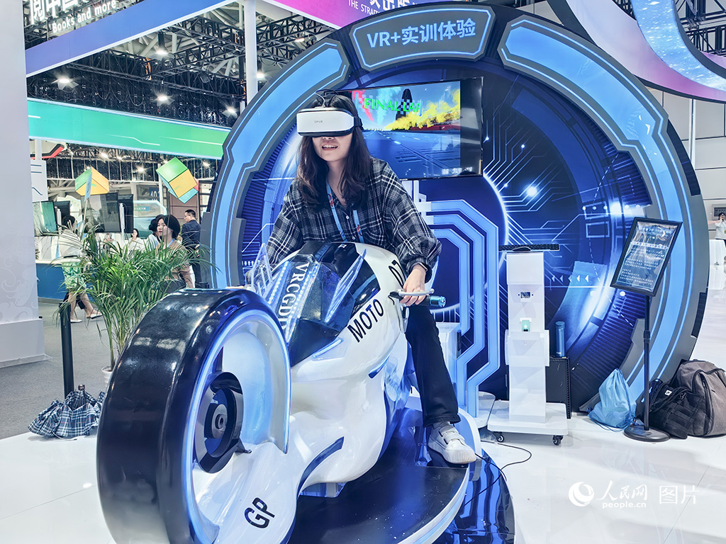 2024年5月23日，第七屆數字中國建設峰會在福建福州開幕。本屆峰會取得豐碩成果，共對接簽約新基建、工業互聯網、人工智能等數字經濟領域項目421個，總投資2030億元，為福建數字化發展注入新動能。圖為市民正在體驗VR摩托車競速項目。人民網 葉青卿 攝