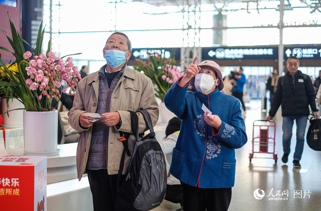 昆明火車站兩位老人正通過大屏查詢車次信息。人民網記者 莊志斌攝