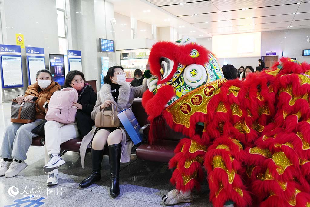 2025年春運首日，河南新鄉東站開展“鄉約伴旅途 非遺迎新春”活動，旅客與醒獅互動。人民網記者 肖懿木攝