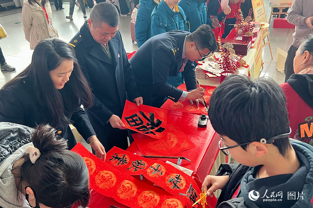 2025年春運首日，成都東站“文明有禮 福暖新春”活動現場，工作人員正在為大家題寫春聯。人民網 趙祖樂攝