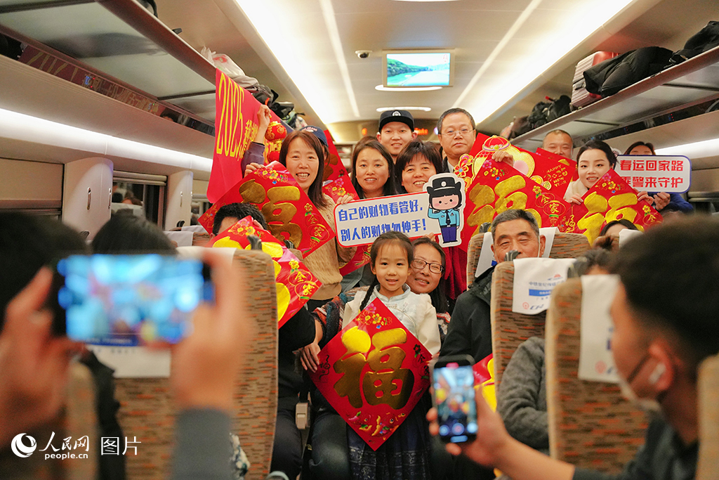 1月13日，在G486次列車上石家莊鐵路公安處民警，為旅客送“?！弊?、普及乘車安全知識并合影留念。人民網記者 周博攝