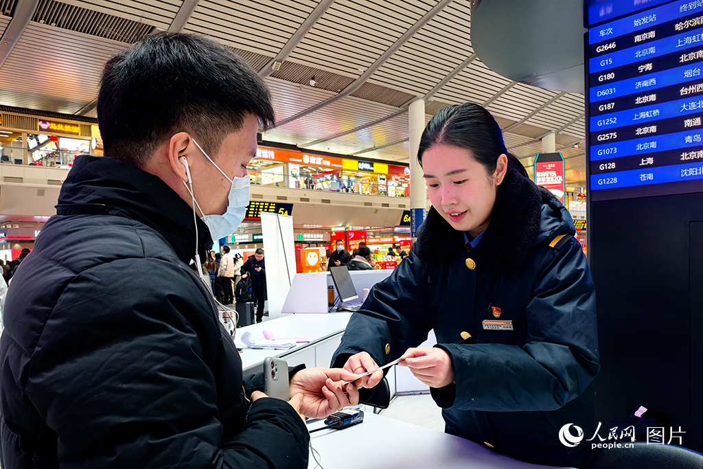 1月13日，濟南西站客服中心的客運員根據旅客的換乘需求，在提示卡上標記路線，幫助旅客便捷換乘。人民網記者 劉祺攝