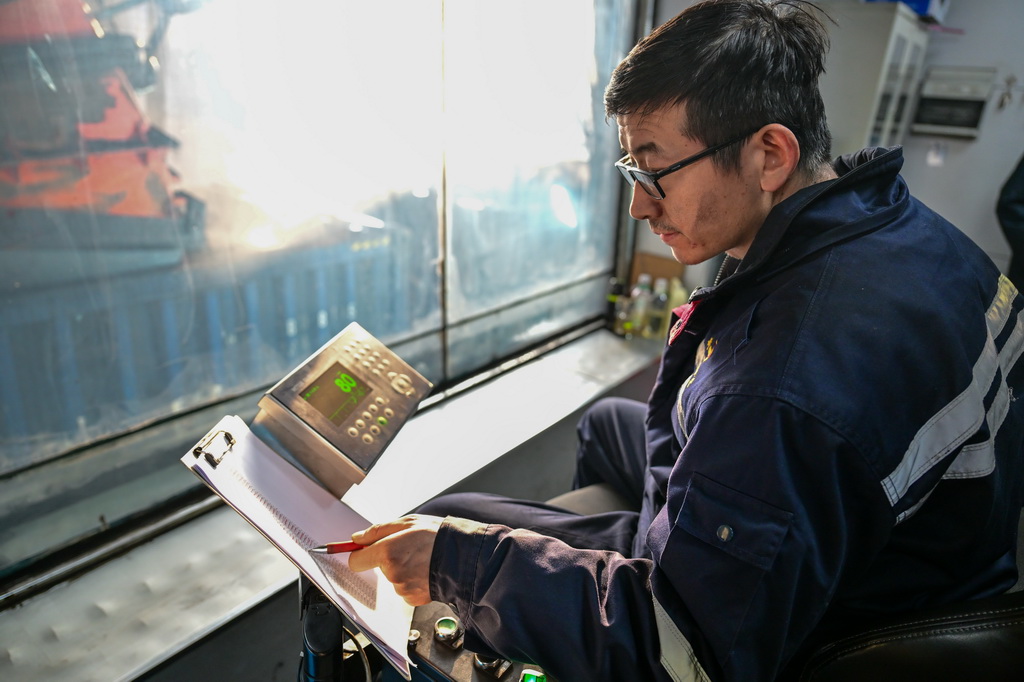 在新疆準東經濟技術開發區內的新疆宜化礦業有限公司煤礦快裝站，工作人員操作設備為出疆的“百輛萬噸”貨運列車裝煤（1月20日攝）。