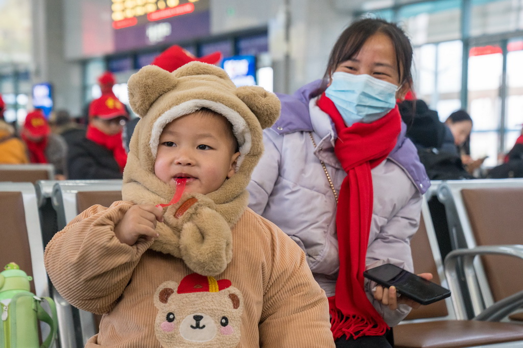 2月5日，一名務工專列的小乘客在廣南縣站候車廳吃零食。