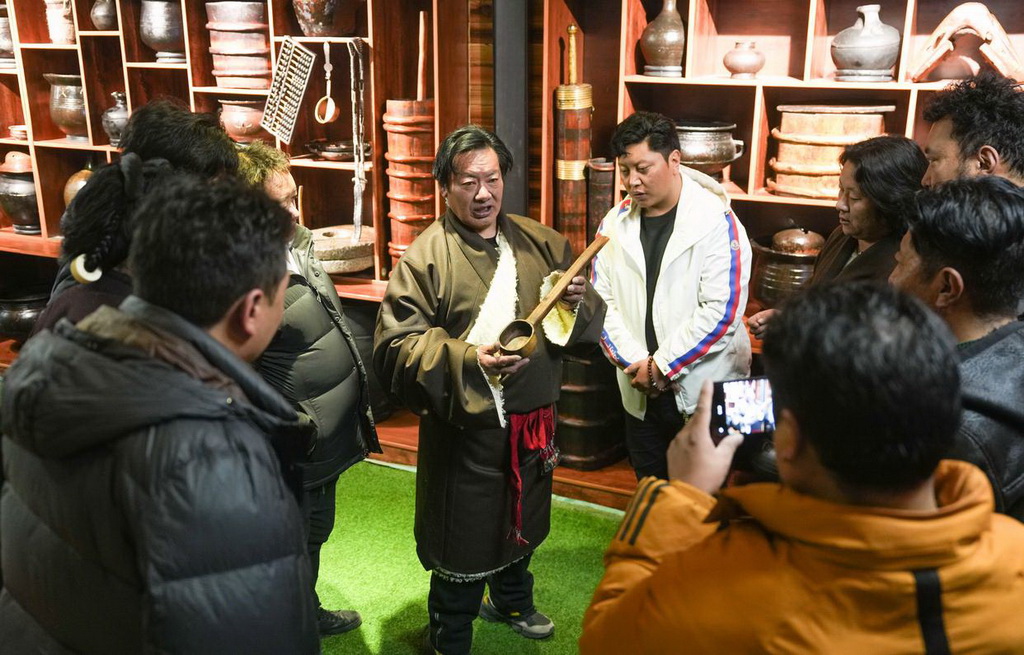 當地民俗專家貢布洛旺（中左）在“牧人寶庫”藏式茶館給顧客講解館藏物件（2月13日攝）。