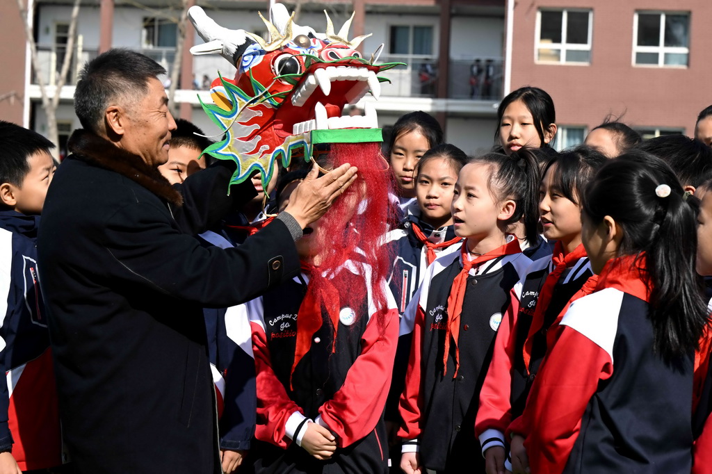 2月26日，王彥州在石家莊市草場街小學給孩子們講解龍風箏制作技藝。新華社發（陳其保攝）